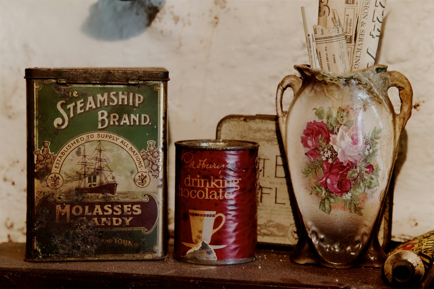 Vintage tins and a floral vase sit on a shelf.