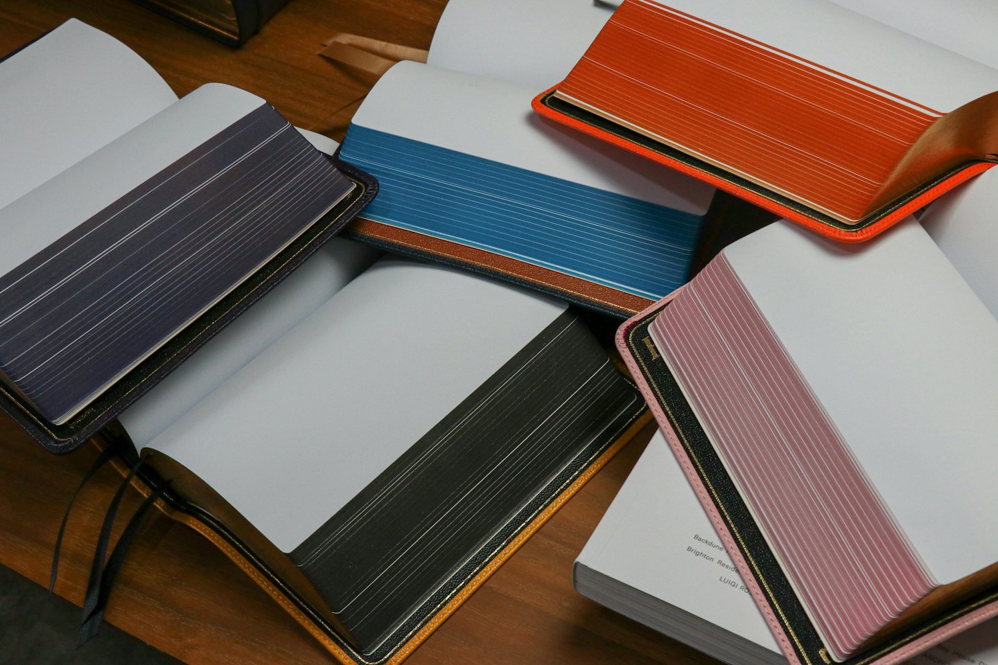 Several open books with colorful page edges lie on wood.